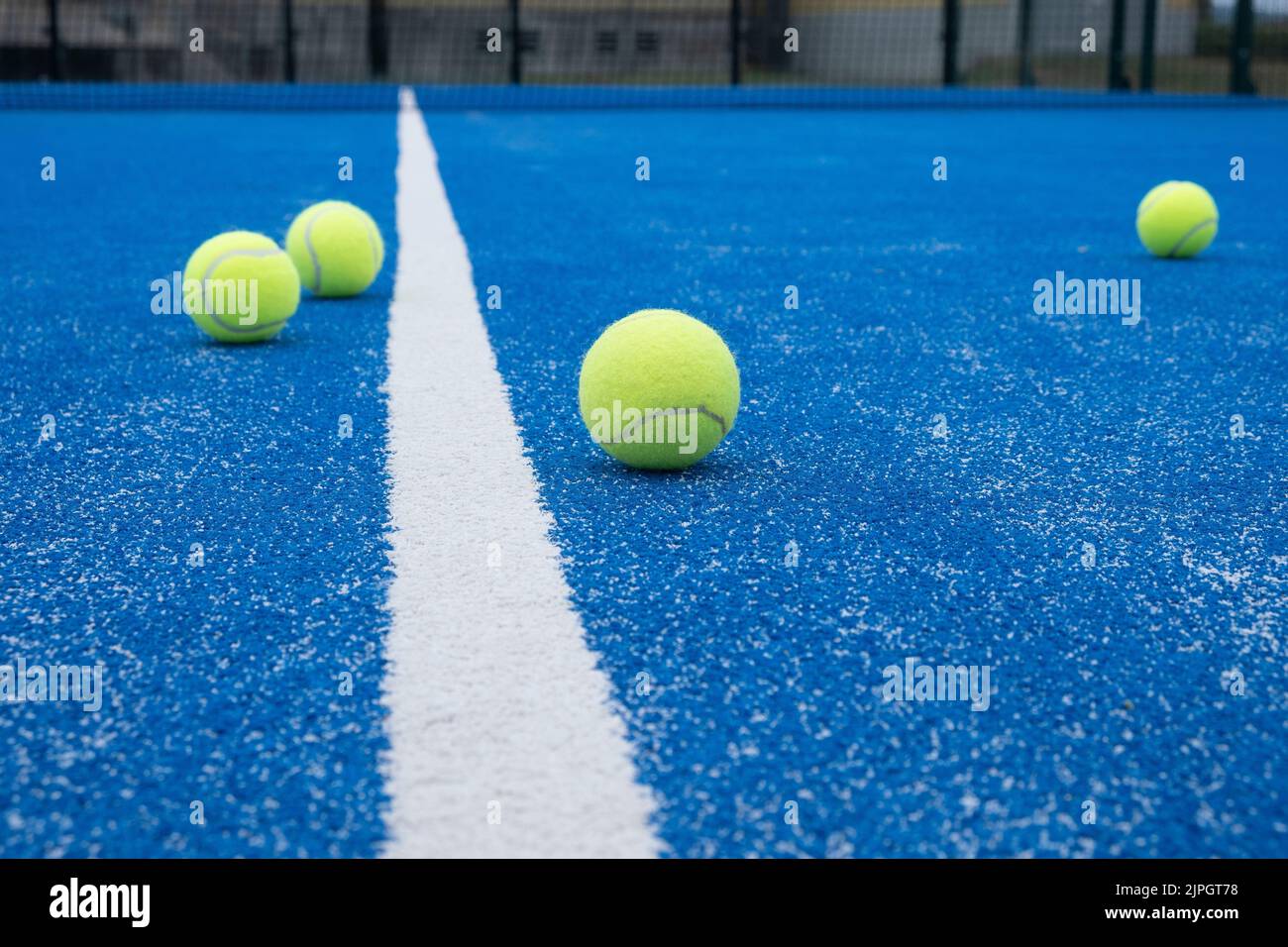 Selective focus. Blue paddle tennis court with synthetic grass and several yellow balls Stock