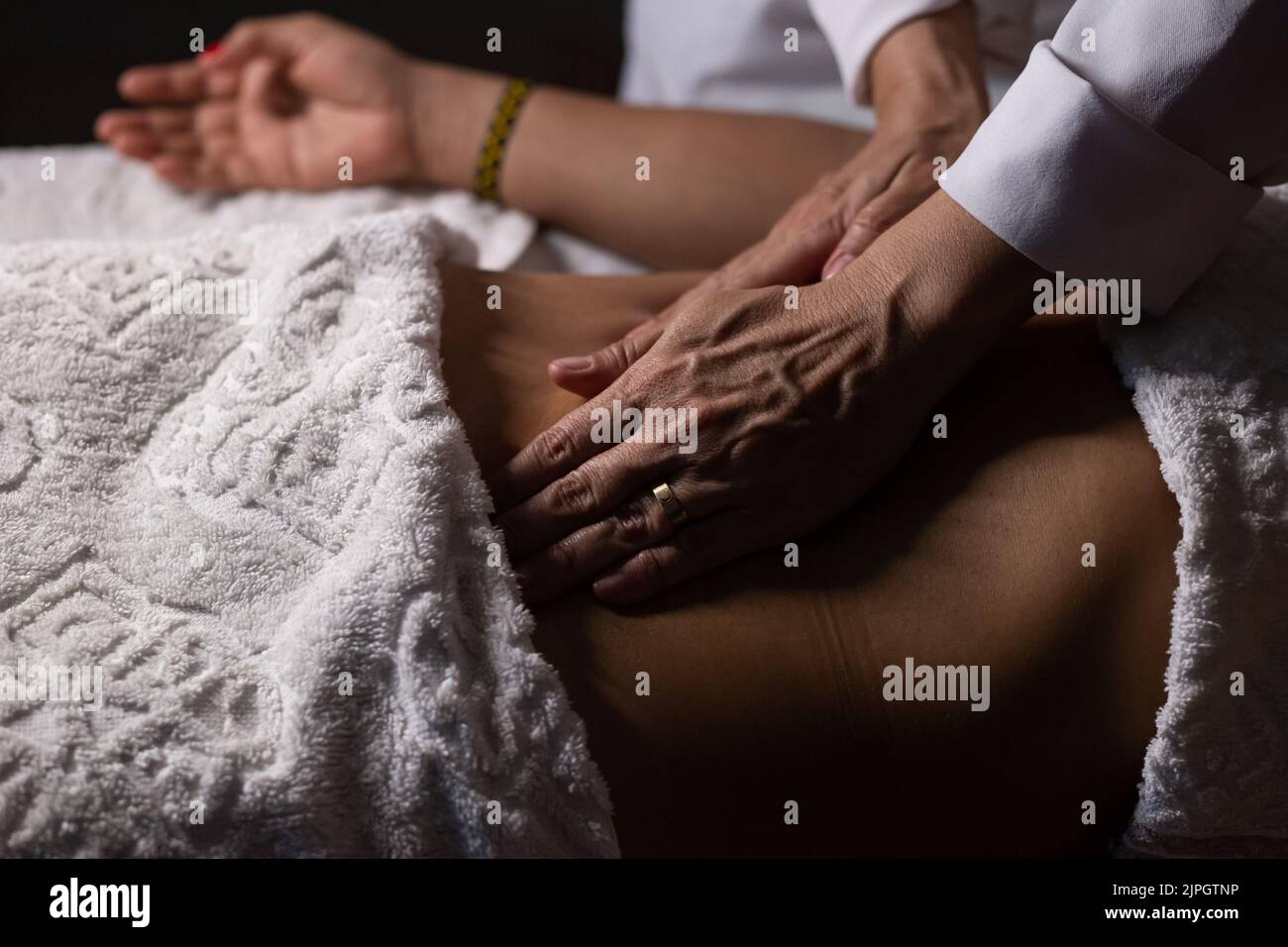 Goiânia, Goias, Brazil – July 18, 2022: Closeup of massage therapist hands applying therapeutic massage on a patient's belly. Stock Photo