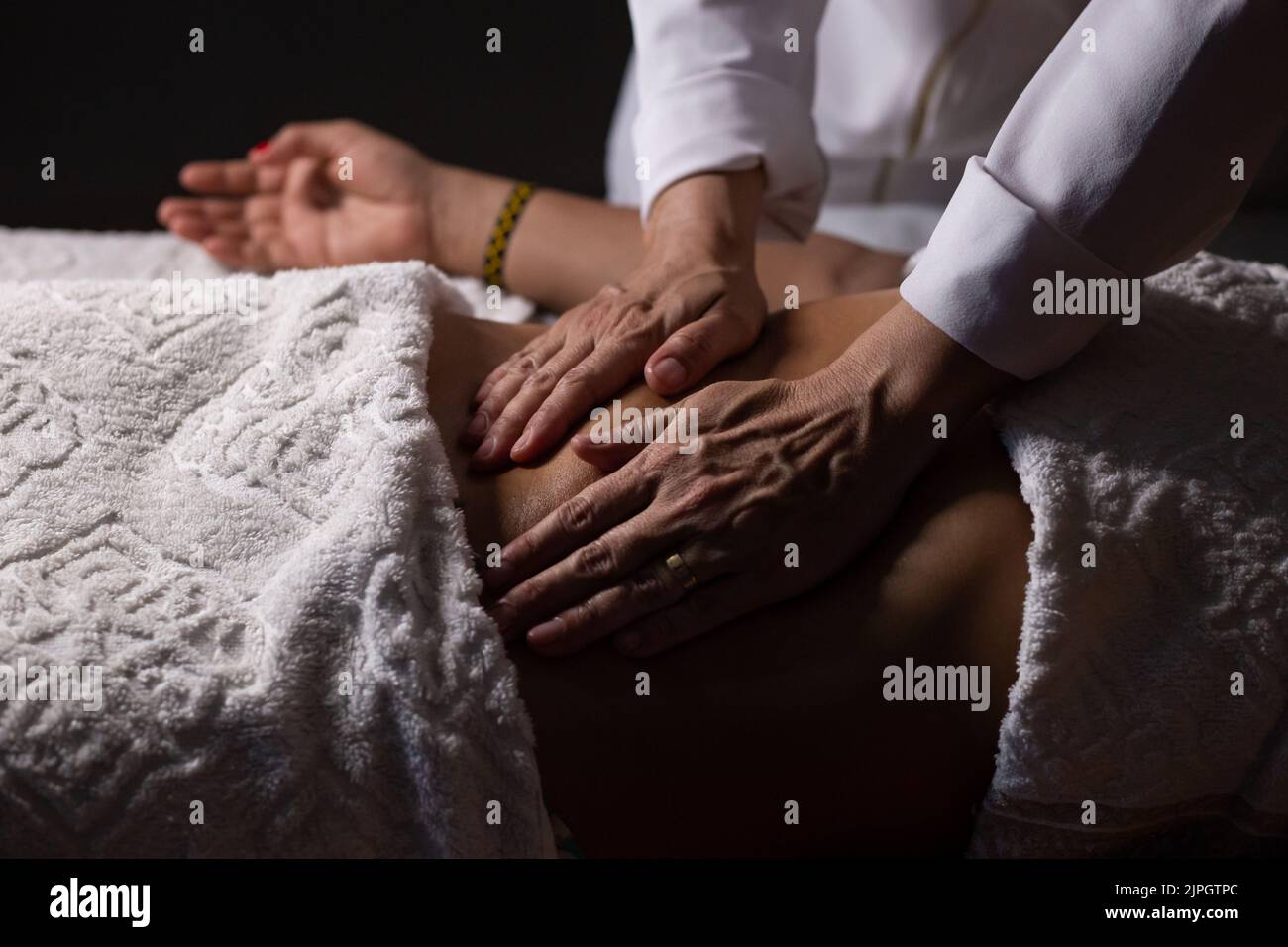 Goiânia, Goias, Brazil – July 18, 2022: Closeup of massage therapist hands applying therapeutic massage on a patient's belly. Stock Photo