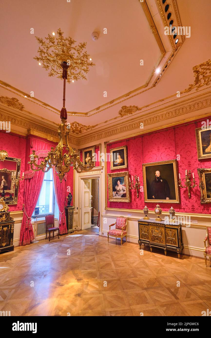 A room with red wallpaper and Old Master paintings. At the Wallace Collection Museum in London, England, United Kingdom. Stock Photo