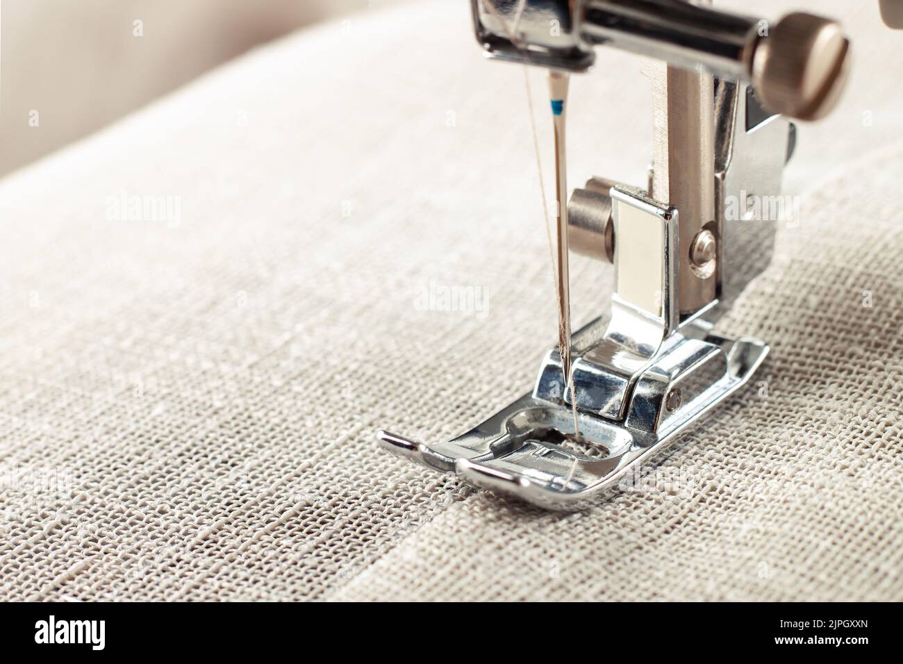 Modern sewing machine presser foot with linen fabric and thread ...