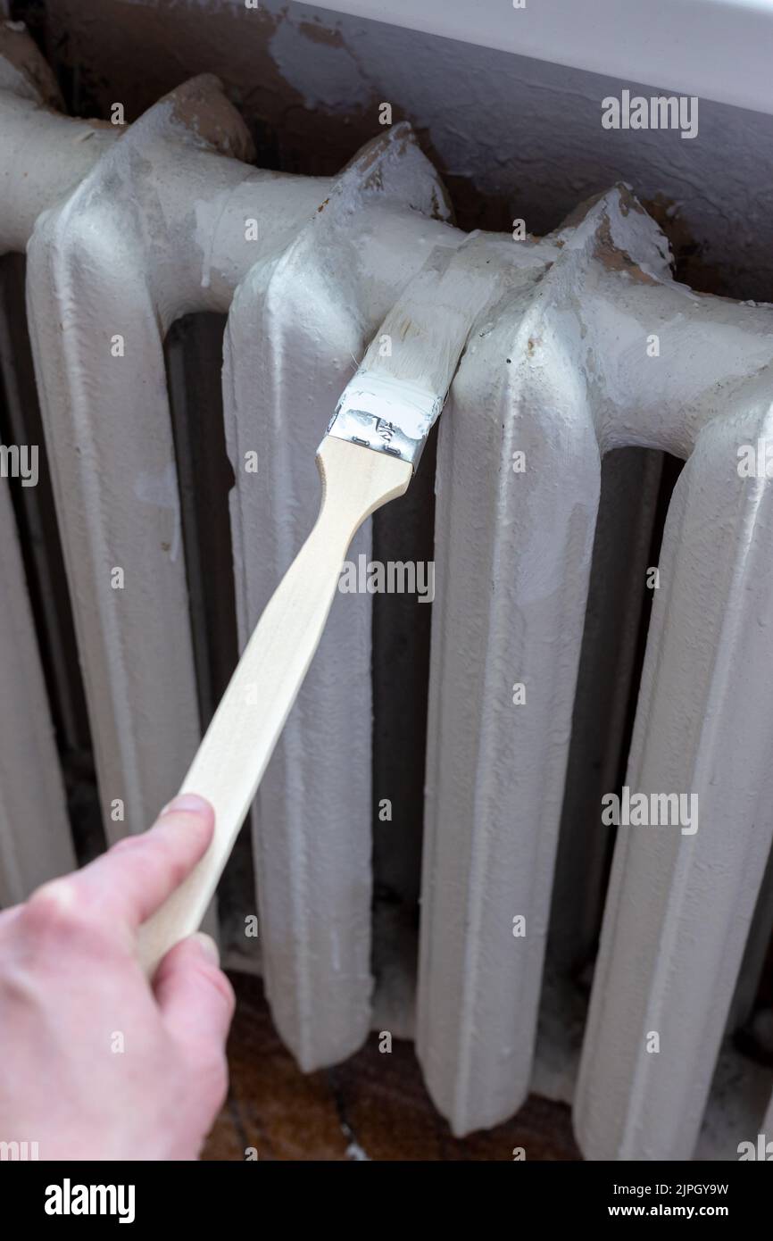 Painting radiators with a special brush. Battery painting Stock Photo