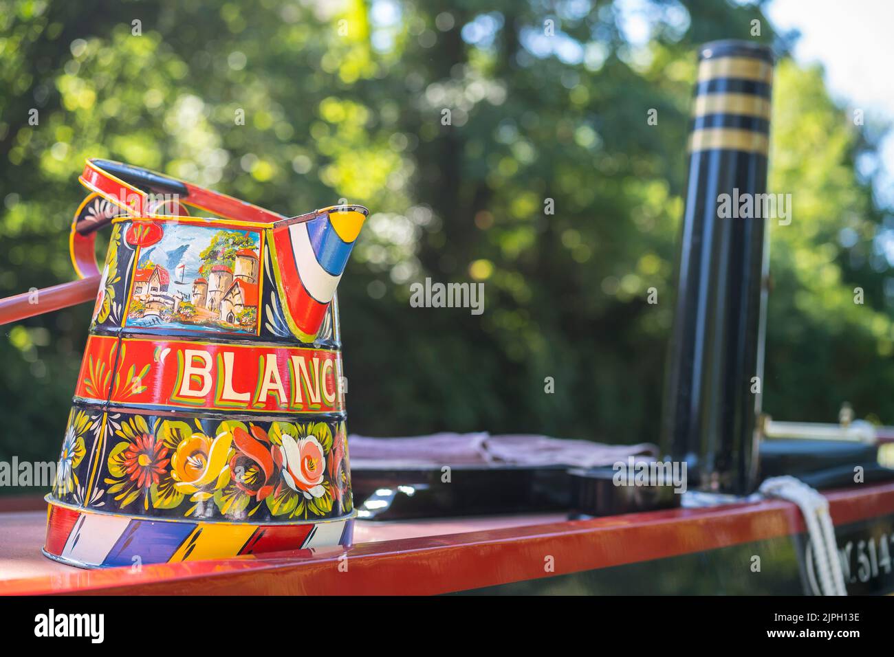 Close up of decorated canal boat water bucket and chimney funnel at the front end of UK canal boat on a sunny summer day. Stock Photo