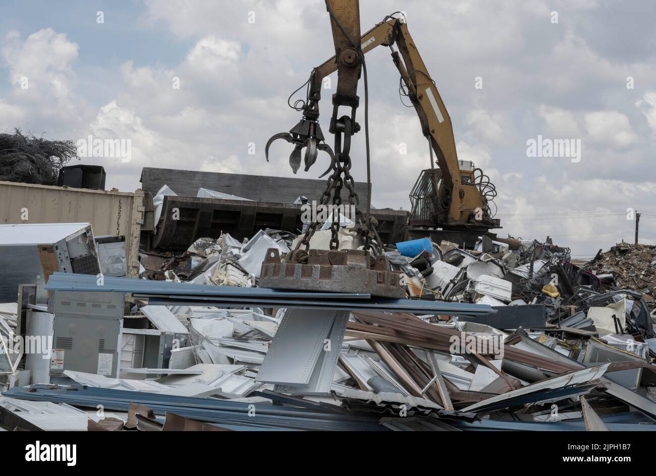 A large Caterpillar track material handler with an attached magnet takes metal construction debris off a utility trailer for recycling at CMC Metals in north Austin, Texas. The yard recycles thousands of pounds of old materials daily. ©Bob Daemmrich Stock Photo