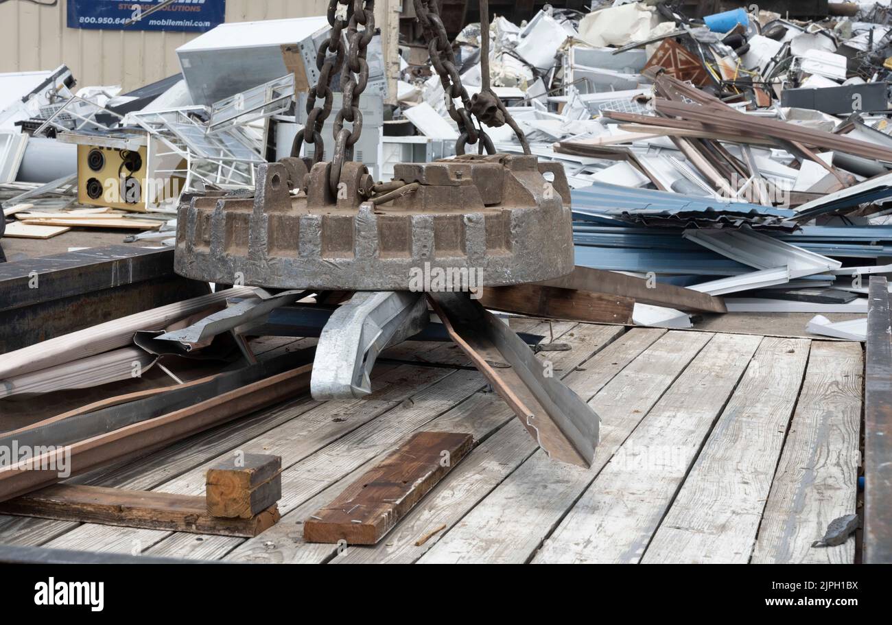 A large Caterpillar track material handler with an attached magnet takes metal construction debris off a utility trailer for recycling at CMC Metals in north Austin, Texas. The yard recycles thousands of pounds of old materials daily. ©Bob Daemmrich Stock Photo