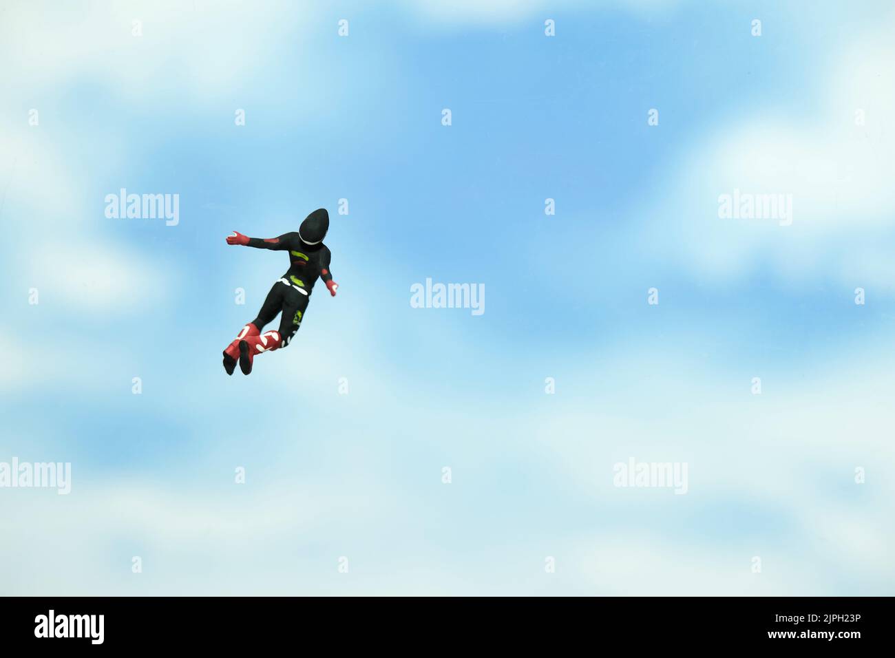 Miniature people toy figure photography. A men doing sky diving jump in cloudy bright day. Image photo Stock Photo