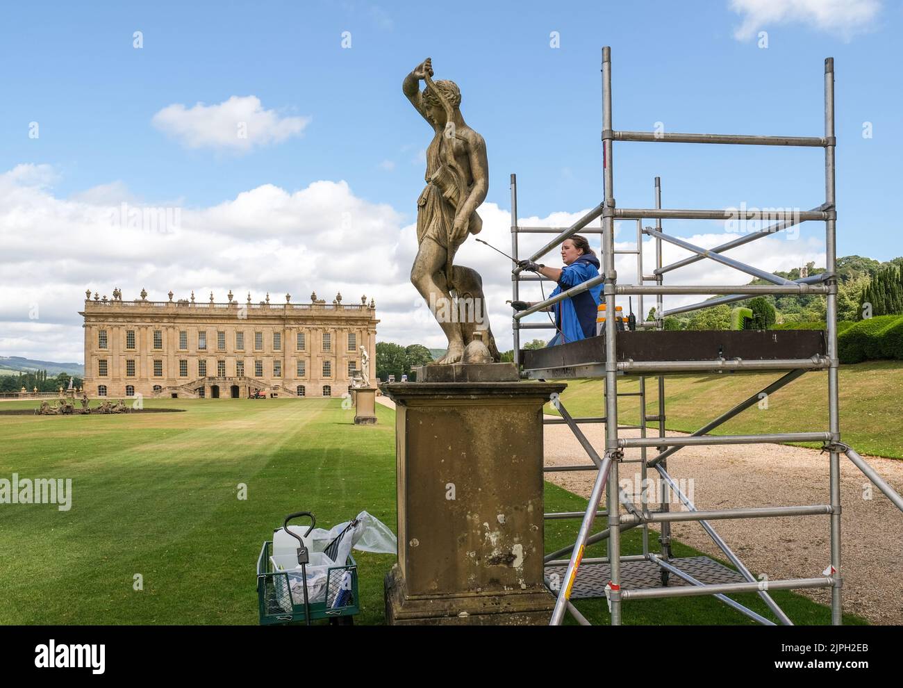A restorer cleaning one of very many carved stone statues in the gardens of Chatsworth House