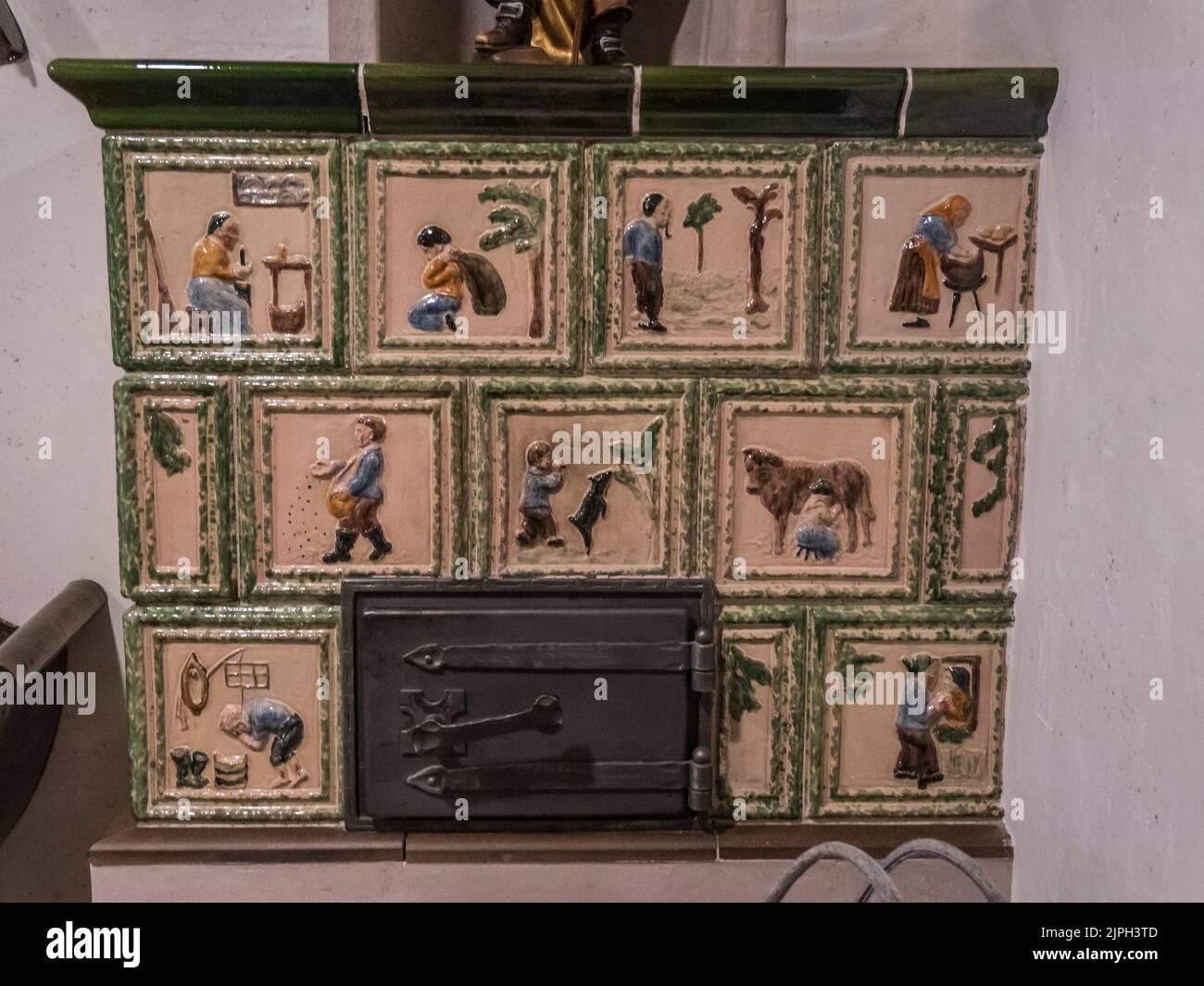 The image is of a Kuchel wood burning stove that is typical within Austrian Tirolean culture with this example depicting various farming scenes Stock Photo