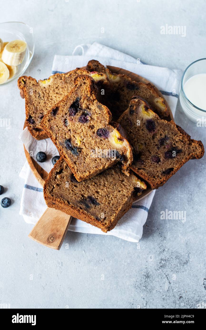 Banana bread slices with blueberries served on a wooden board on a gray background. Top view. Stock Photo
