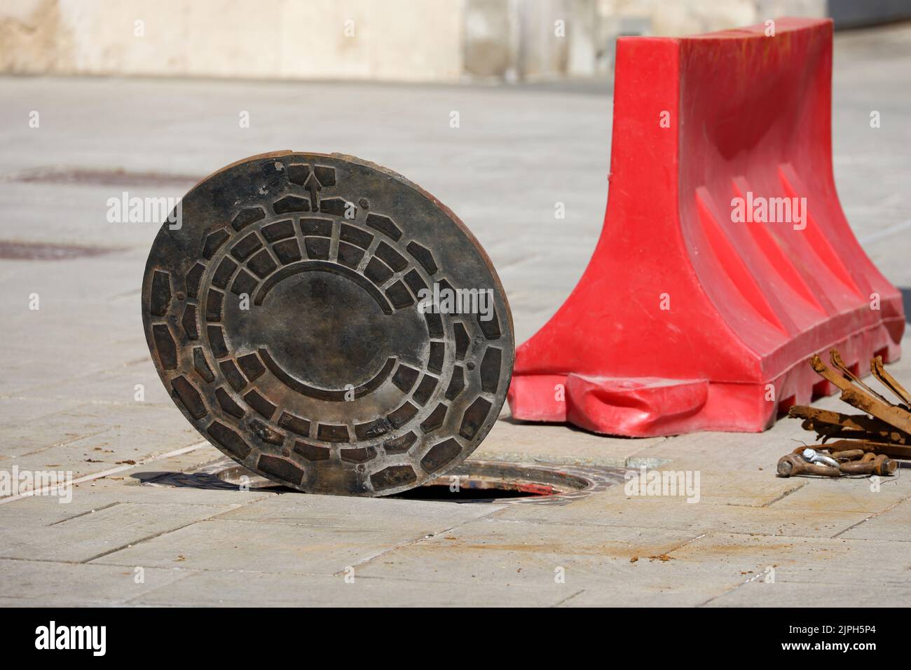 Open sewer hatch and road block on a street. Concept of repair of sewage, underground utilities, water supply system, water pipe accident Stock Photo