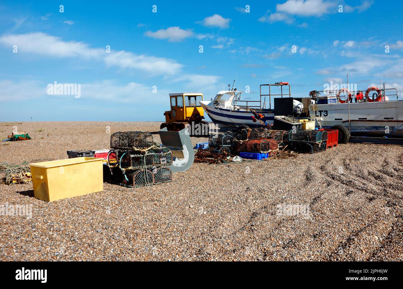 Fishing boats and equipment stored on the shingle beach above high water on the North Norfolk coast at Cley-Next-the-Sea, Norfolk, England, UK. Stock Photo