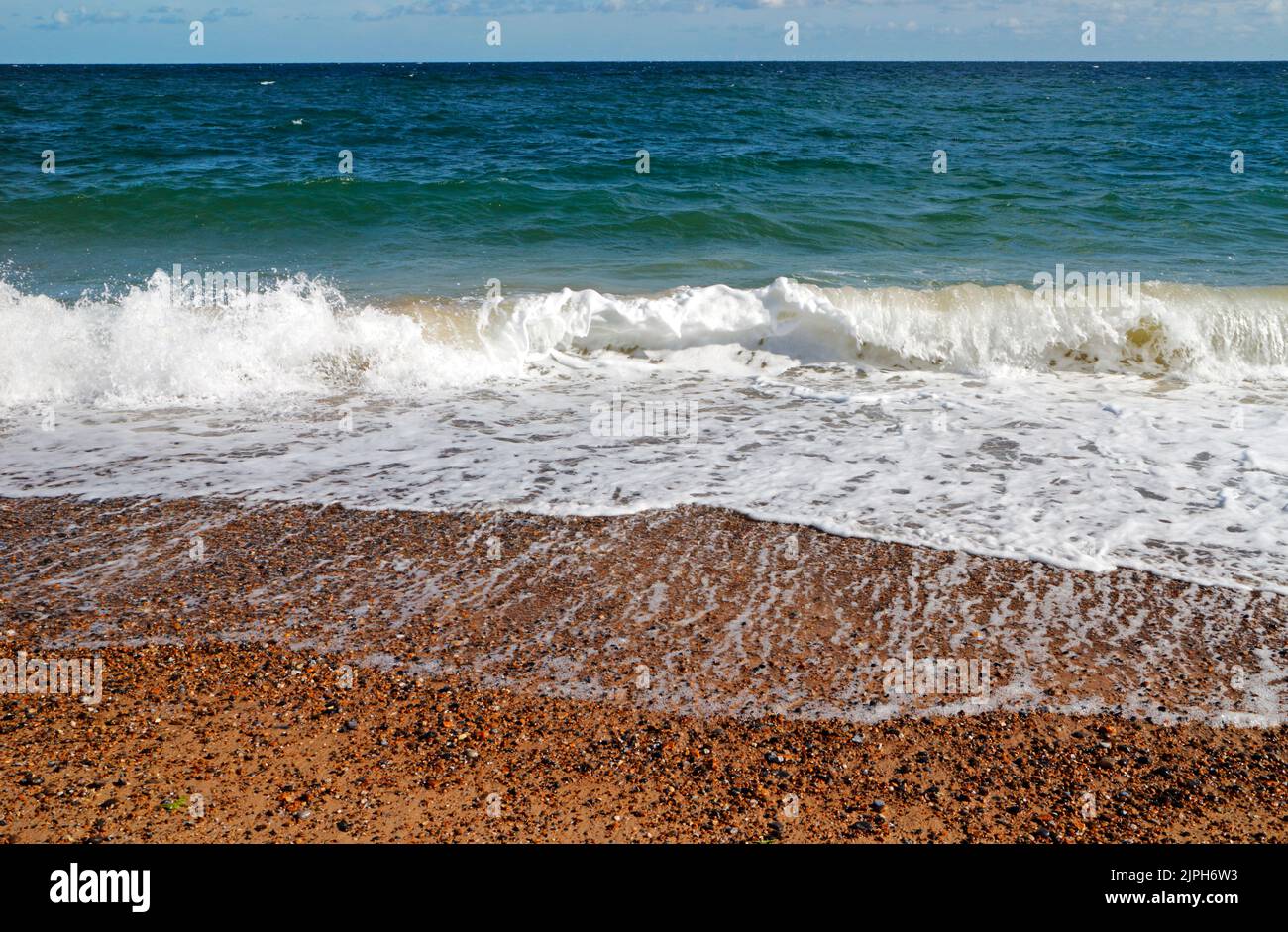 An abstract of waves breaking on the shingle beach in summer in a north-easterly breeze at Cley-Next-the-Sea, Norfolk, England, United Kingdom. Stock Photo