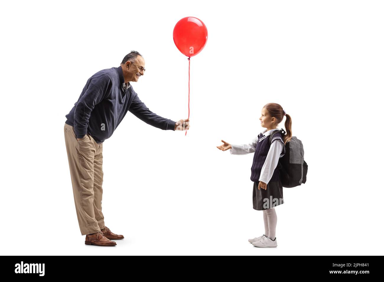 Full length profile shot of a mature man giving a red balloon to a schoolgirl isolated on white background Stock Photo