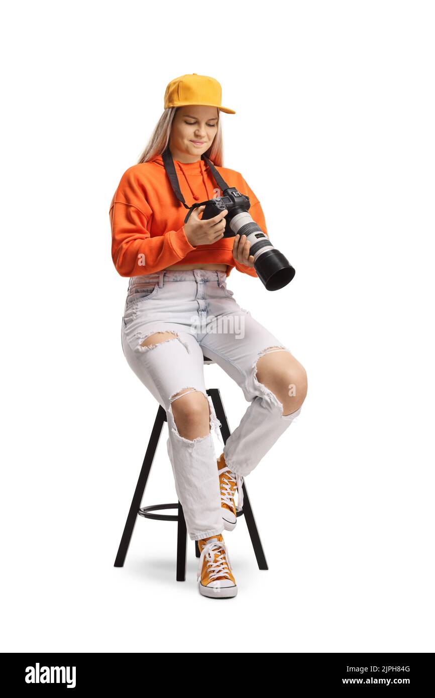 Young female sitting and looking at a display of a professional camera isolated on white background Stock Photo