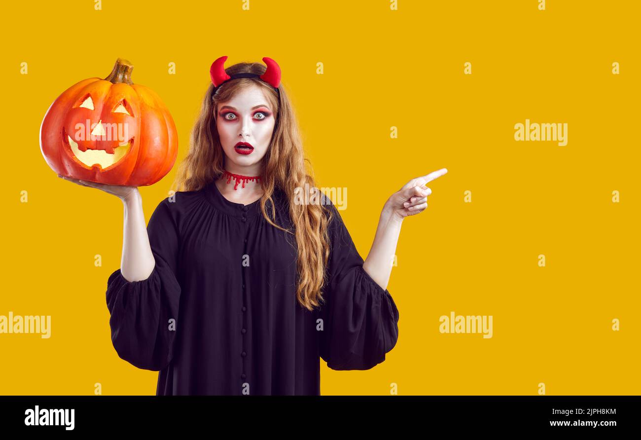 Funny surprised young woman in Halloween costume pointing her finger at copy space Stock Photo