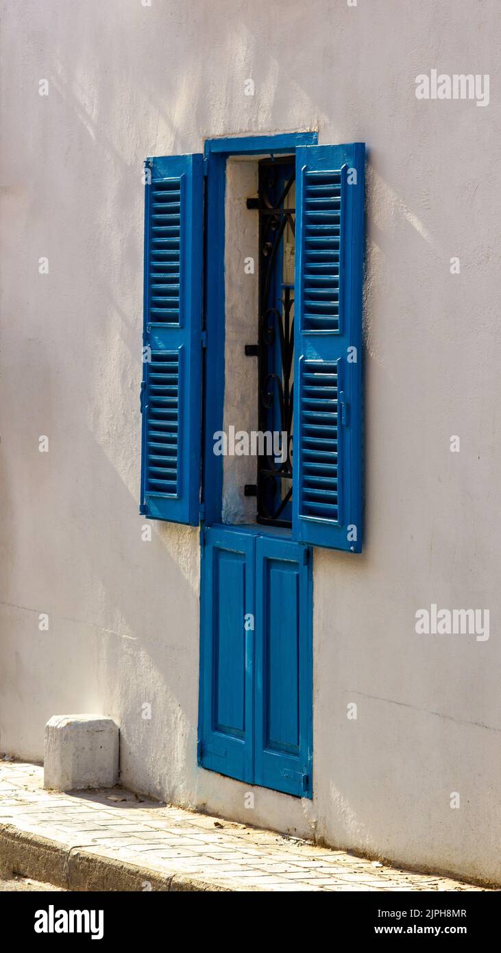 A blue window with louvers with shadows, in Annibale Preca Street, Lija
