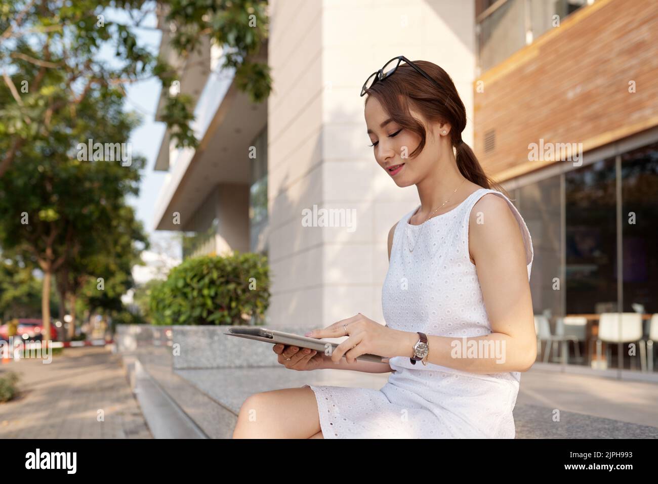 Smiling Vietnamese young woman using application on tablet computer Stock Photo