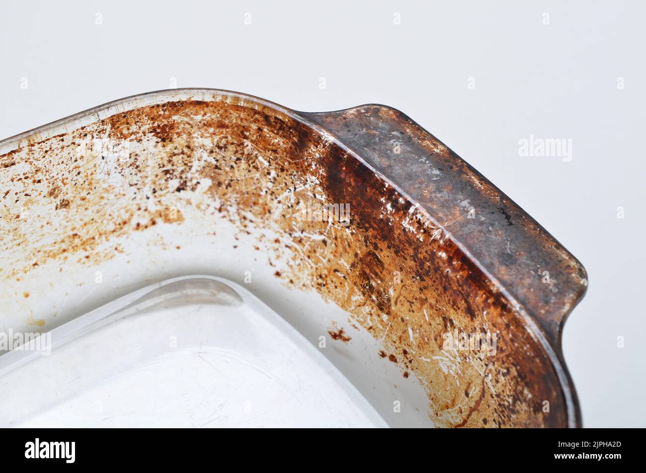 Corner of oven proof glass pyrex dish showing burnt on cooking Stock