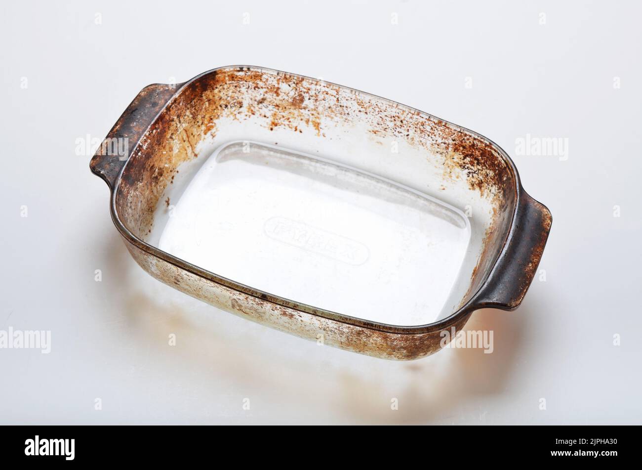 Glass pyrex oven dish used with burnt food on the edges on white