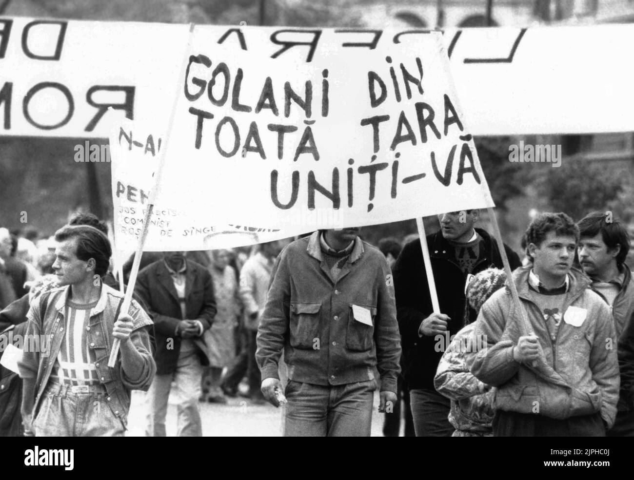 Bucharest, Romania, April 1990. 'Golaniada', a major anti-communism protest  in the University Square following the Romanian Revolution of 1989. People would gather daily to protest the ex-communists that grabbed the power after the Revolution. As president Iliescu called them 'golani' (hooligans), the protesters proudly adopted the term, and wore it as a badge. This people are holding a banner saying 'Hooligans of the country, unite!' Stock Photo