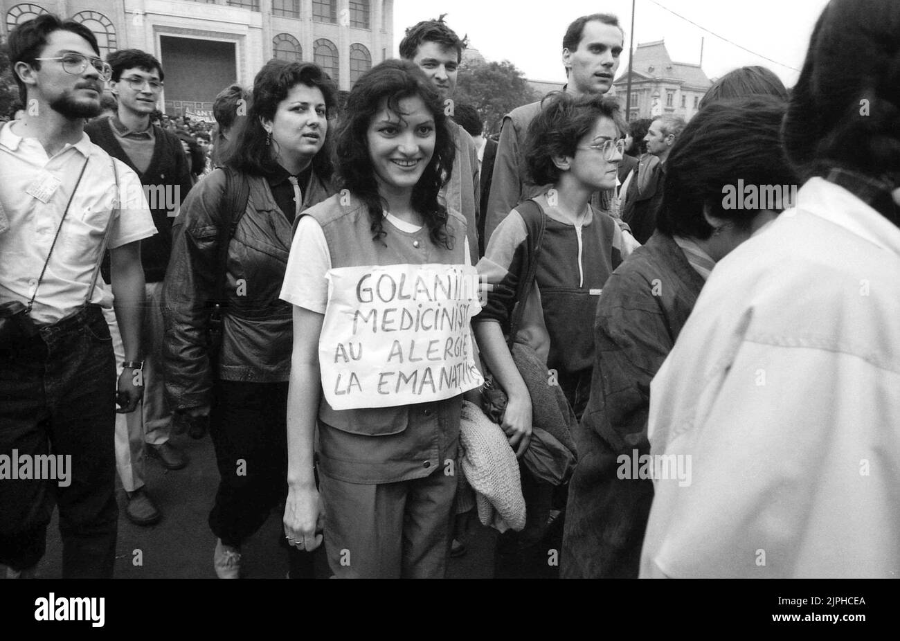 Bucharest, Romania, April 1990. 'Golaniada', a major anti-communism protest  in the University Square following the Romanian Revolution of 1989. People would gather daily to protest the ex-communists that grabbed the power after the Revolution. As president Iliescu called them 'golani' (hooligans), the protesters proudly adopted the term, and wore it as a badge. This woman is wearing a poster saying 'The hooligans studying Medicine are allergic to neocommunists '. Stock Photo