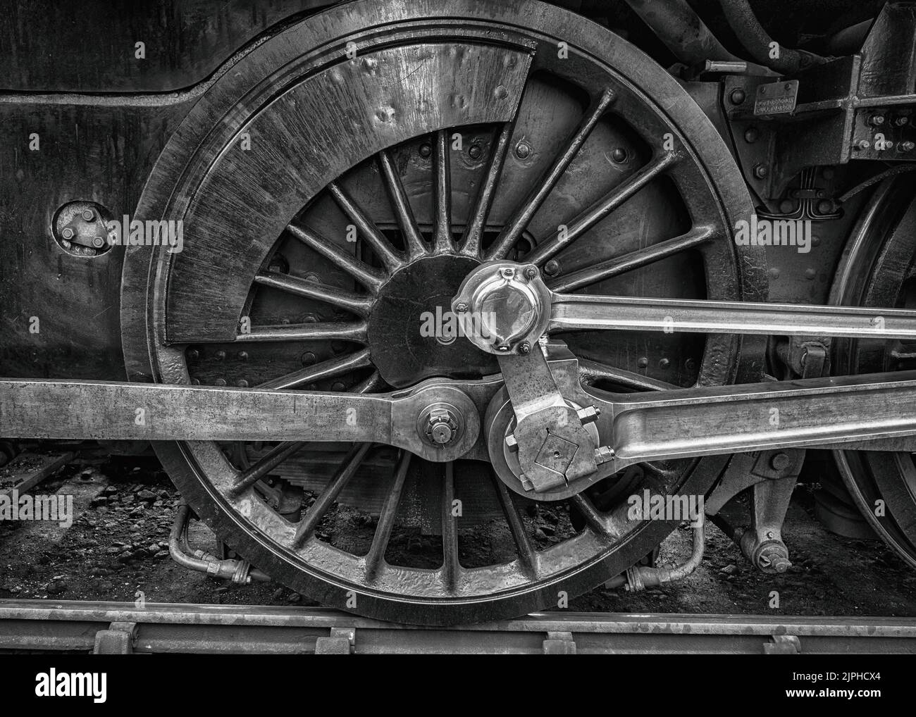 Black and white image of large steel wheels on a steam engine at the Bluebell Railway, East Sussex Stock Photo