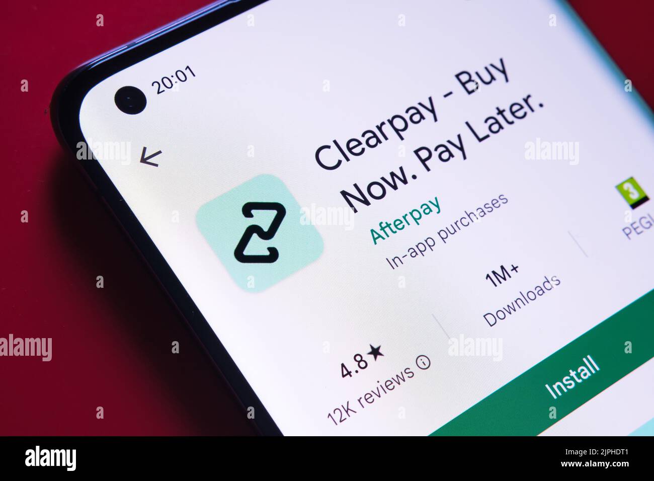 clearpay app seen in Google Play Store on the smartphone screen placed on red background. Close up photo with selective focus. Stafford, United Kingdo Stock Photo