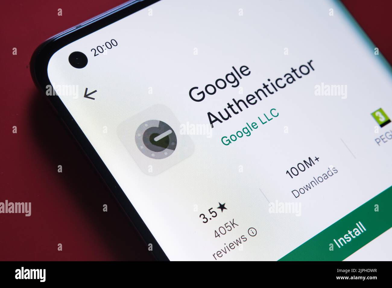 Google authenticator app seen in Google Play Store on the smartphone screen placed on red background. Close up photo with selective focus. Stafford, U Stock Photo