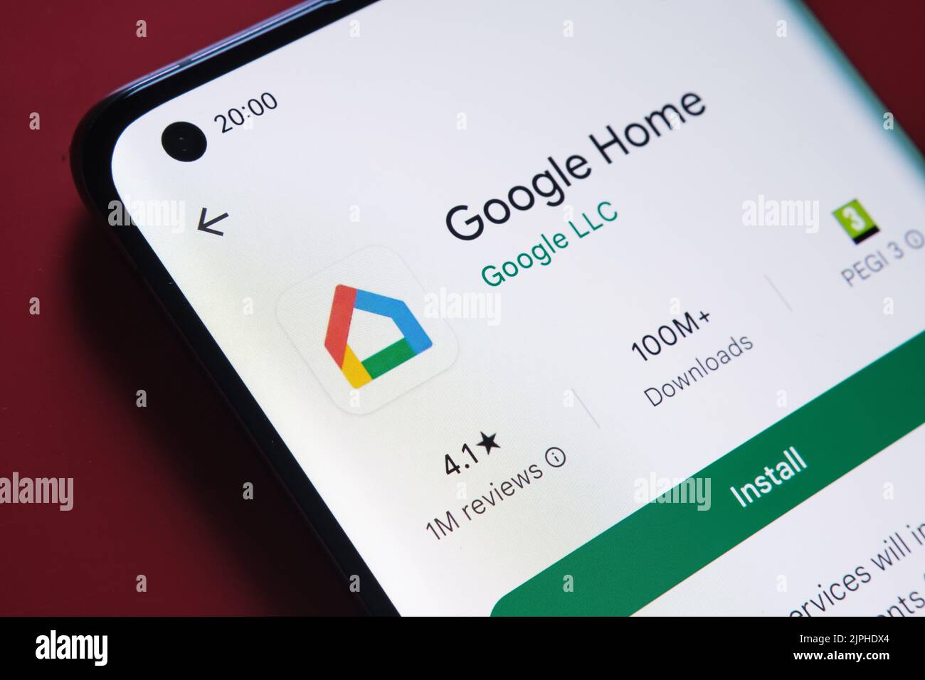 google home app seen in Google Play Store on the smartphone screen placed on red background. Close up photo with selective focus. Stafford, United Kin Stock Photo