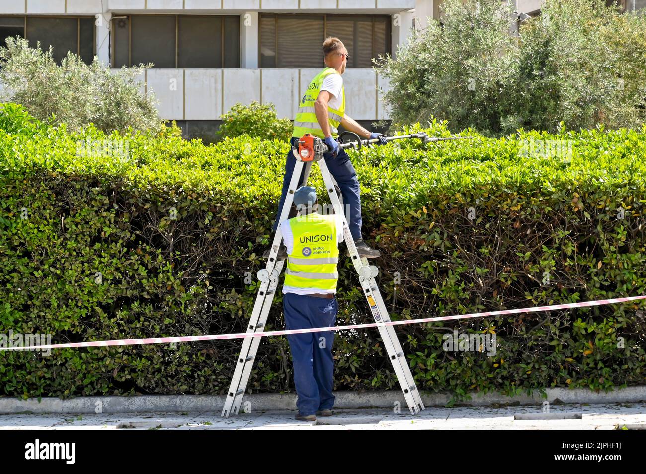 Athens, Greece May 2022 Person using a long handled hedge cutter to