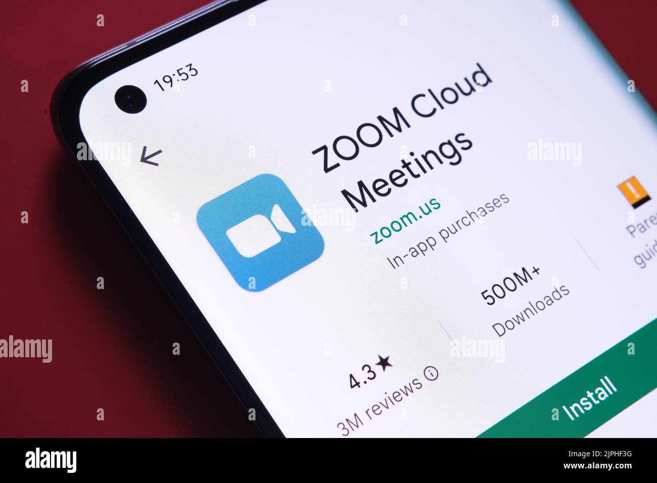 Zoom cloud meetings app seen in Google Play Store on the smartphone screen placed on red background. Close up photo with selective focus. Stafford, Un Stock Photo