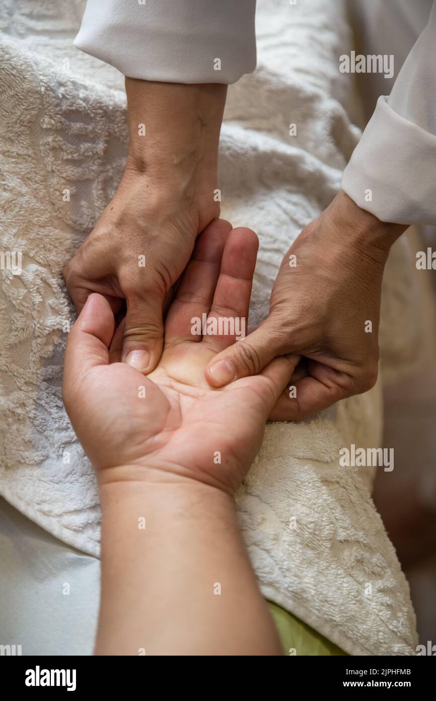 Goiânia, Goias, Brazil – July 18, 2022: Detail of hands of masseur, who is applying therapeutic massage on the hand of a patient who is lying down. Stock Photo