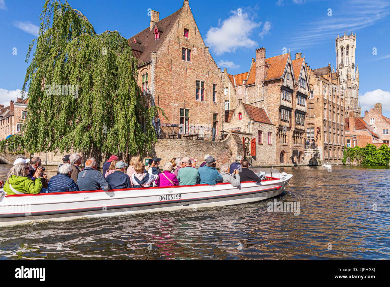 Tourists enjoying a guided boat tour around the canals of Bruges, Belgium Stock Photo