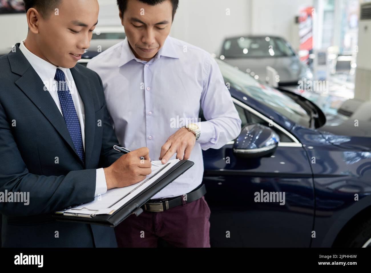 Vietnamese man signing up for test drive at car dealer Stock Photo Alamy