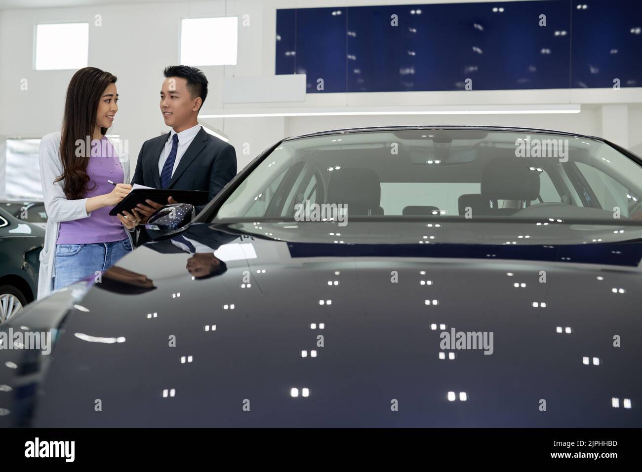 Sales man shoing young woman where to sign document for the new car Stock Photo