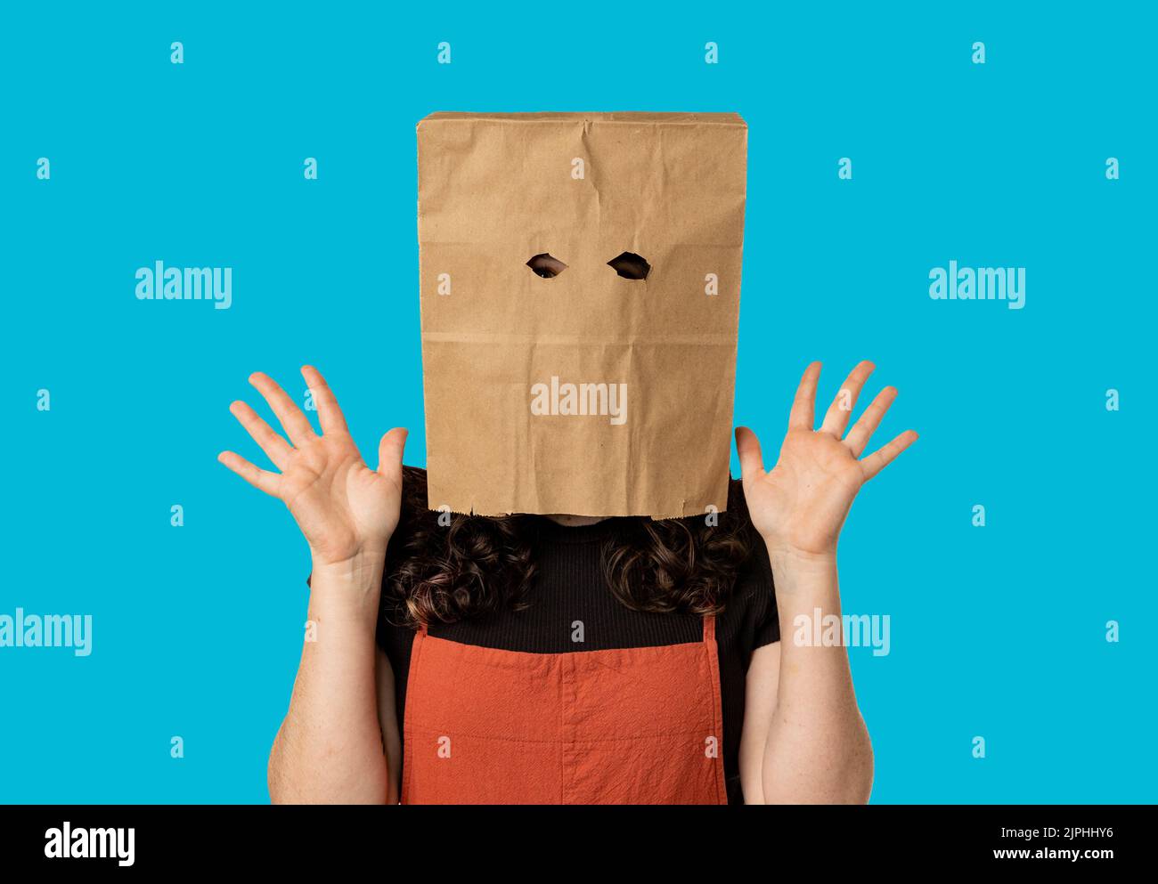 Woman wearing paper bag over her head looking surprised Stock Photo