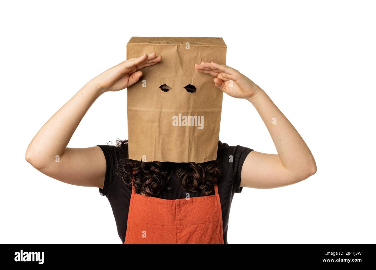 Woman wearing paper bag over her head with hands above eyes, searching. Stock Photo
