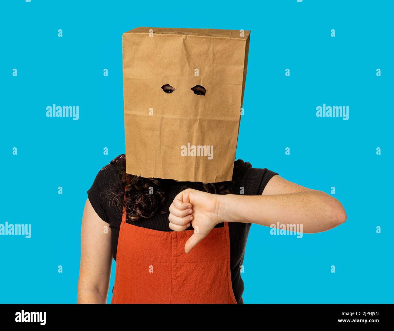 Young woman wearing paper bag over her head giving thumbs down. Stock Photo