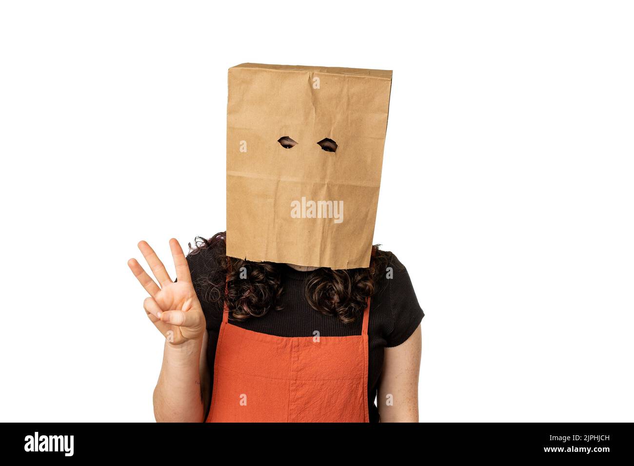 Young woman wearing paper bag over her head holding up three fingers Stock Photo