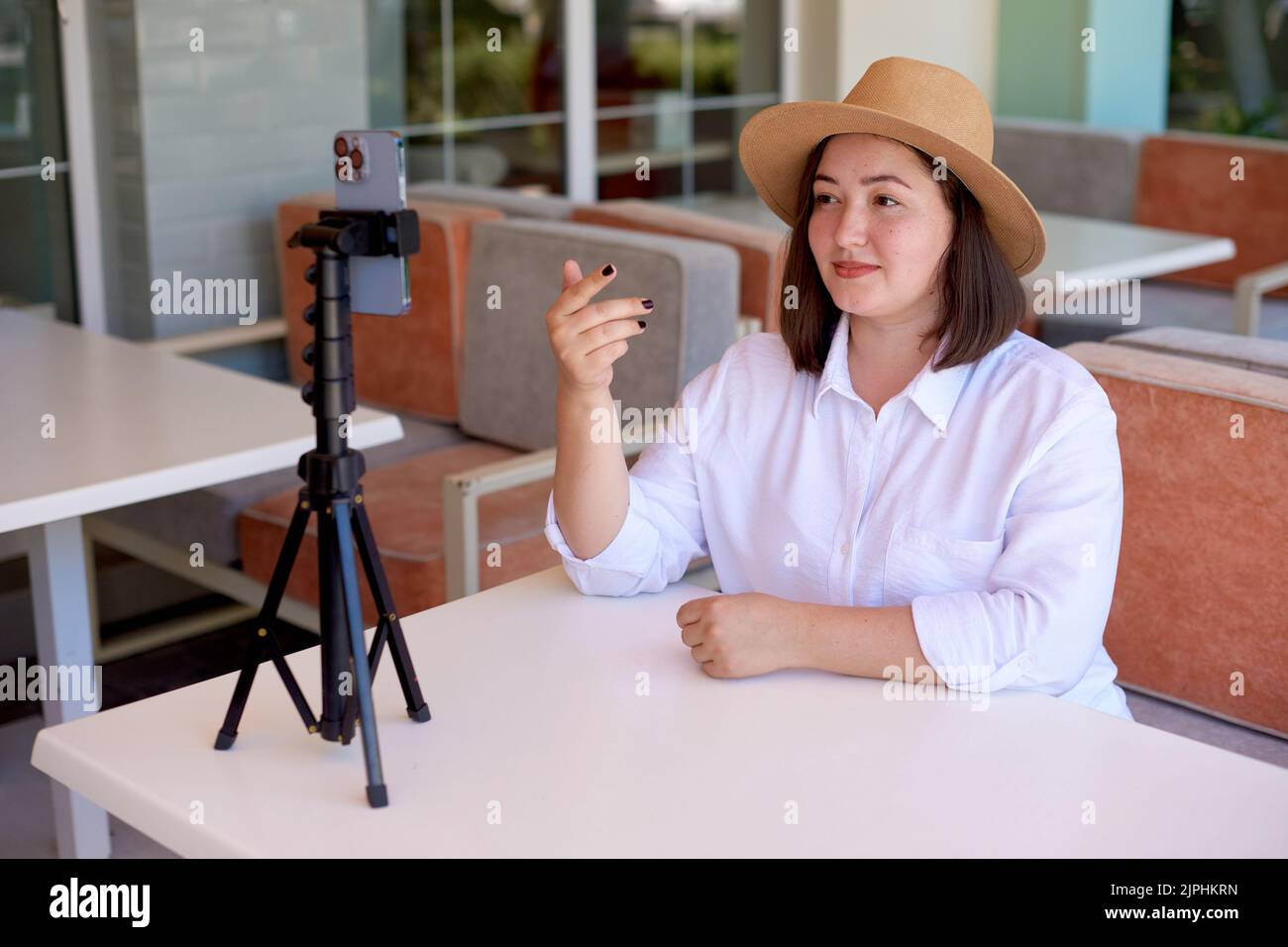 Woman blogger leads Live Video for social networks in cafe. Freelance distance media working. shallow depth of field Stock Photo