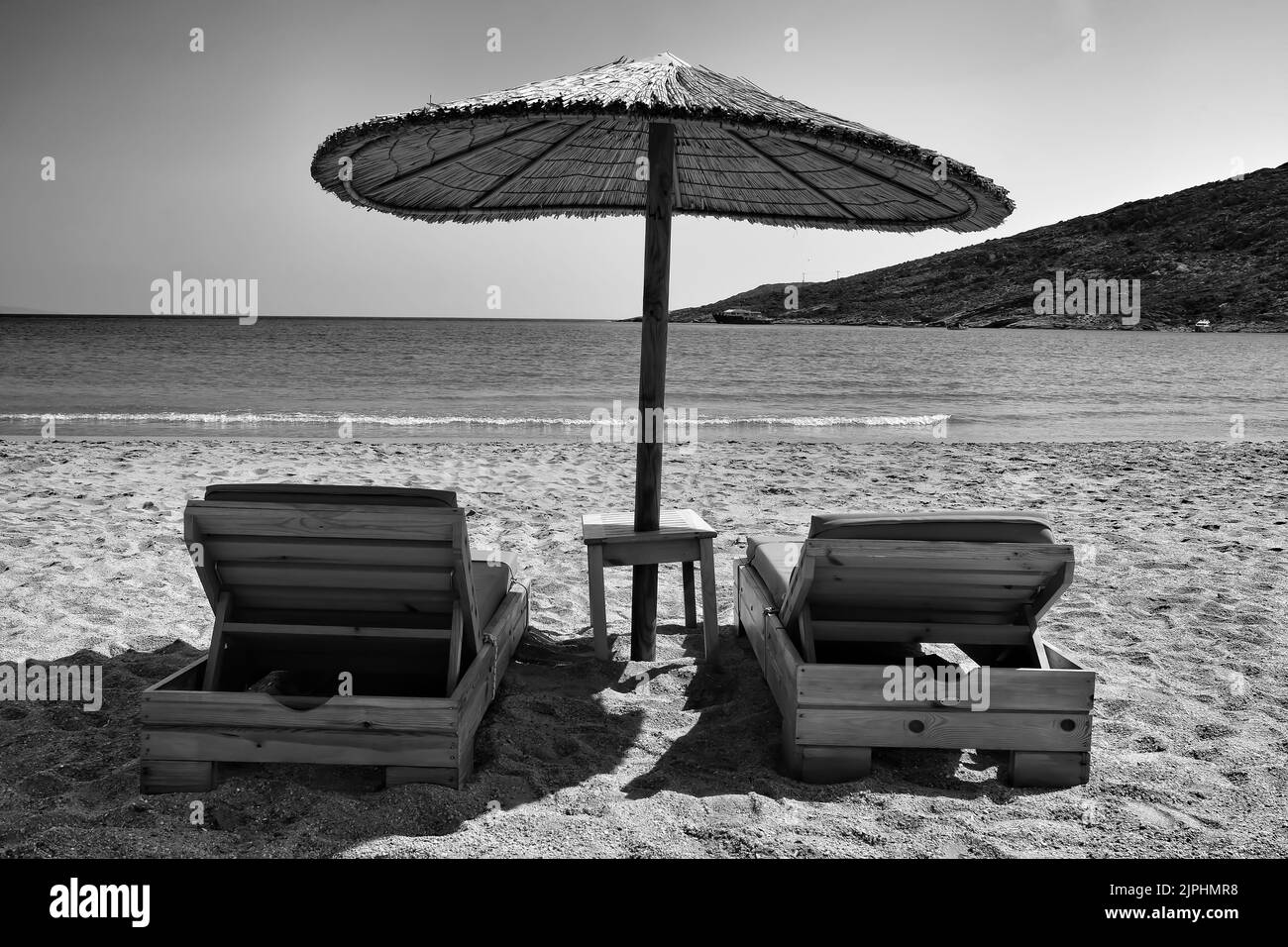 Two sunbeds and a sun umbrella at the amazing beach of Manganari in Ios