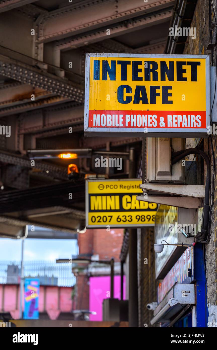 LONDON - May 20, 2022: Internet Cafe and Mini Cabs signs on side of building Stock Photo