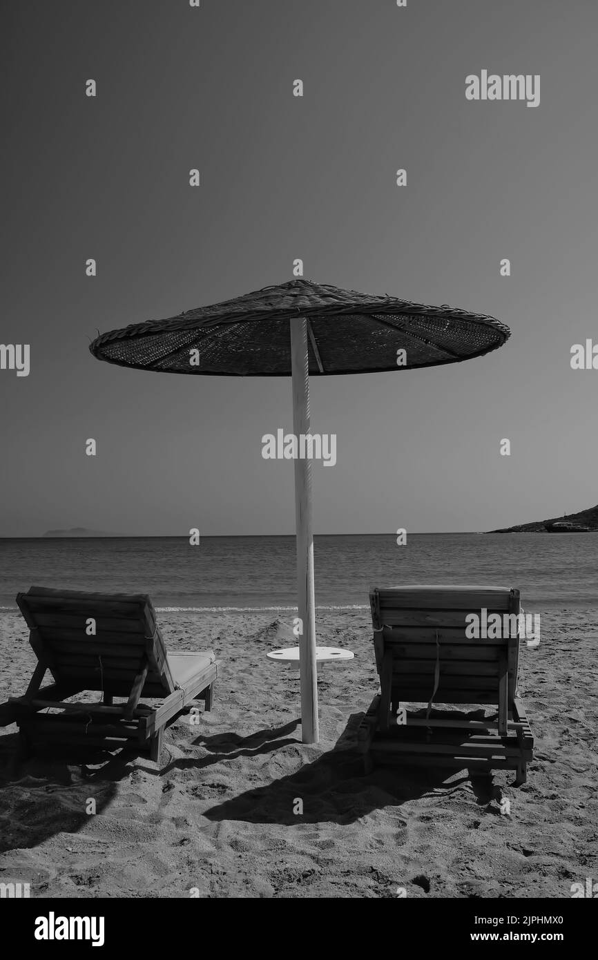 Two sunbeds and a sun umbrella at the amazing beach of Manganari in Ios