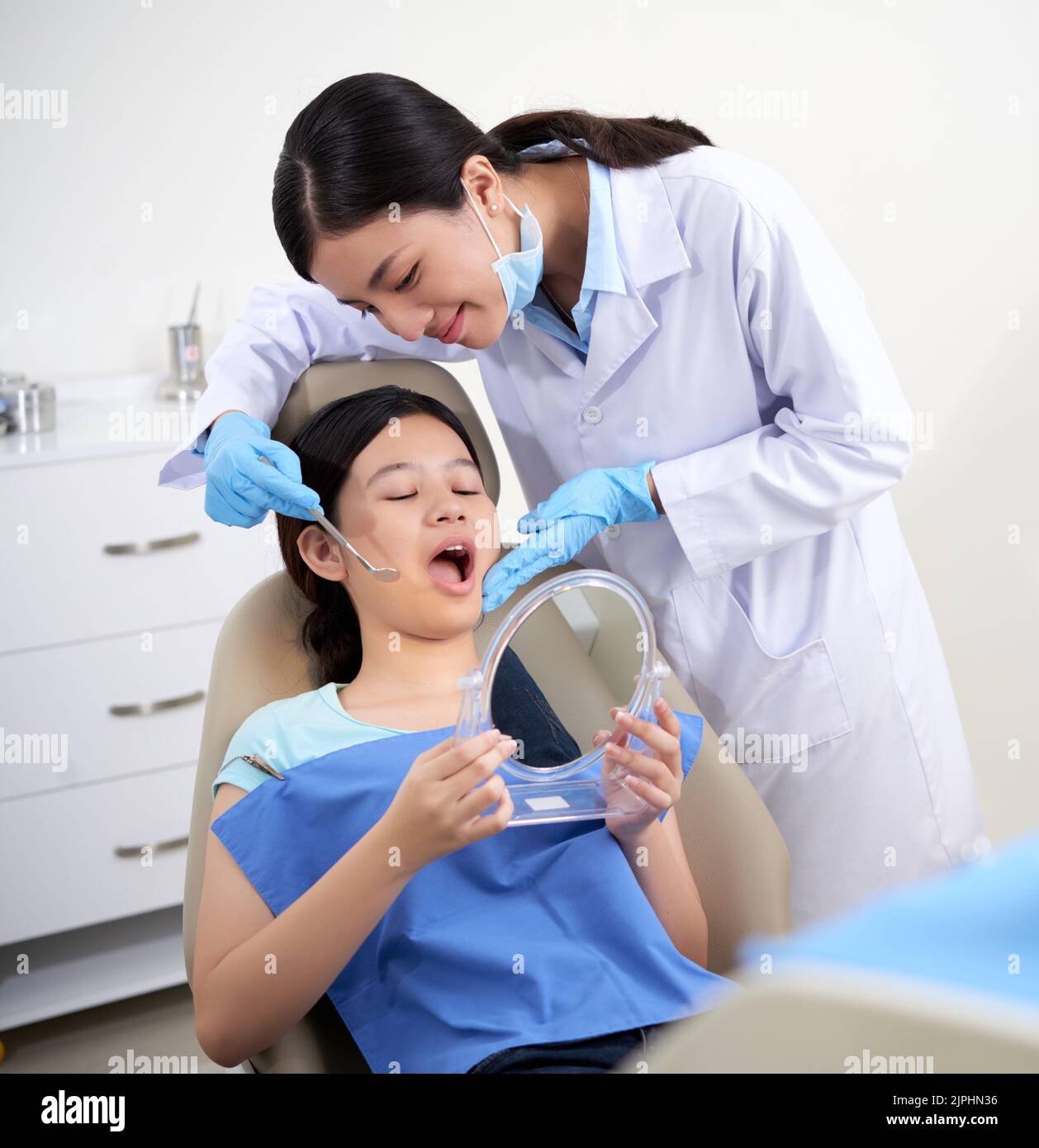 Teenage dentistry pateint with mirror looking at her treated teeth Stock Photo Alamy