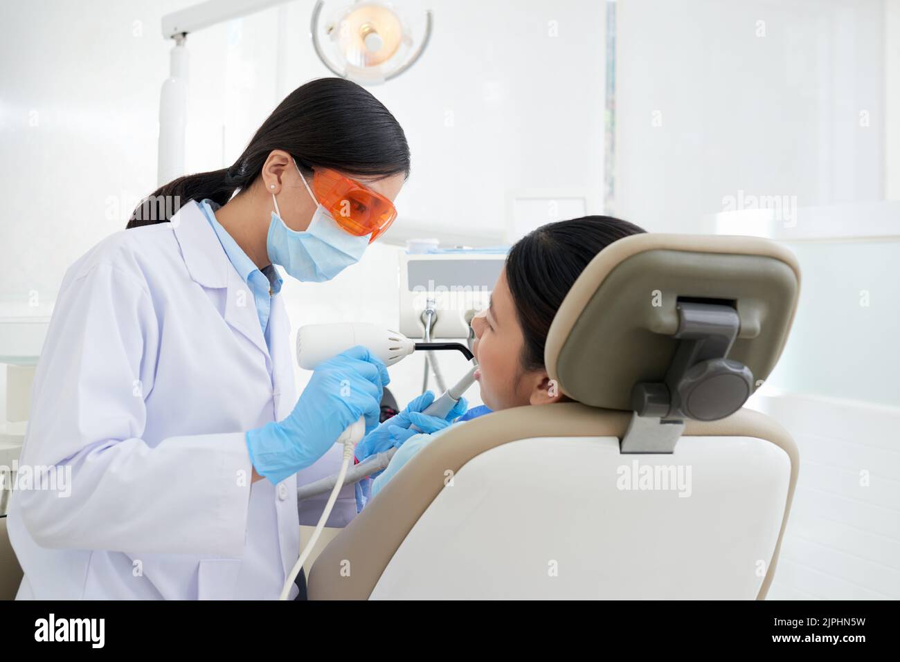 Young Vietnamese dentist fixing teeth of female patient Stock Photo Alamy