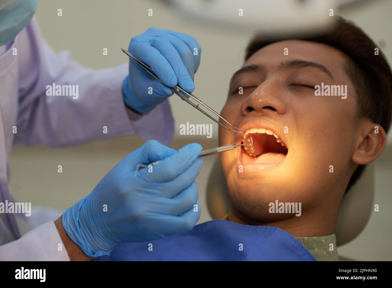 Vietnamese young man having his teeth examined at dentist office Stock Photo Alamy