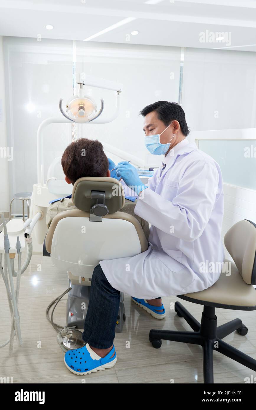 Vietnamese middleaged dentist examining teeth of patient Stock Photo Alamy
