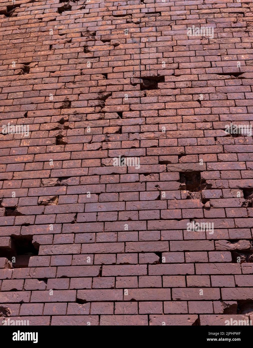An old brick wall with various damages, the wall is old and made of