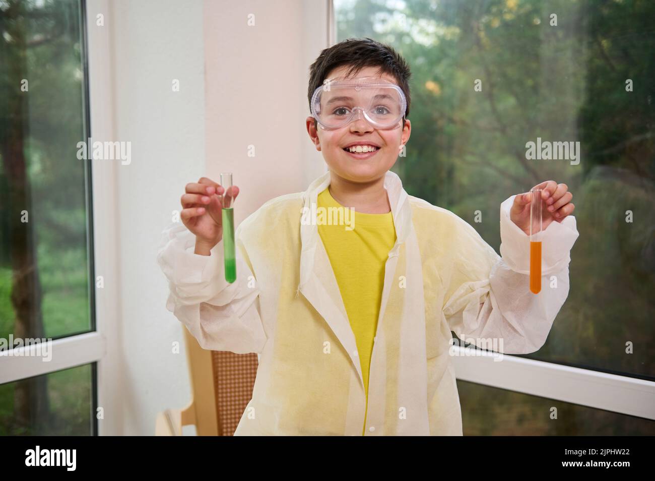 Cheerful little chemist scientist, schoolboy in safety goggles and lab