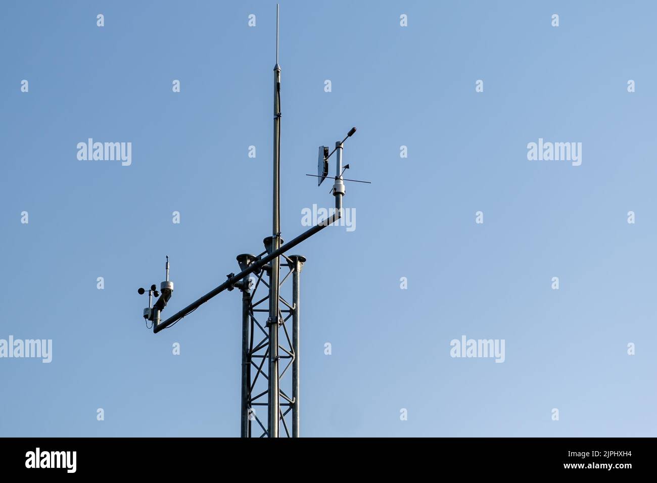 Communication antenna pole stands against clear blue sky. High antenna